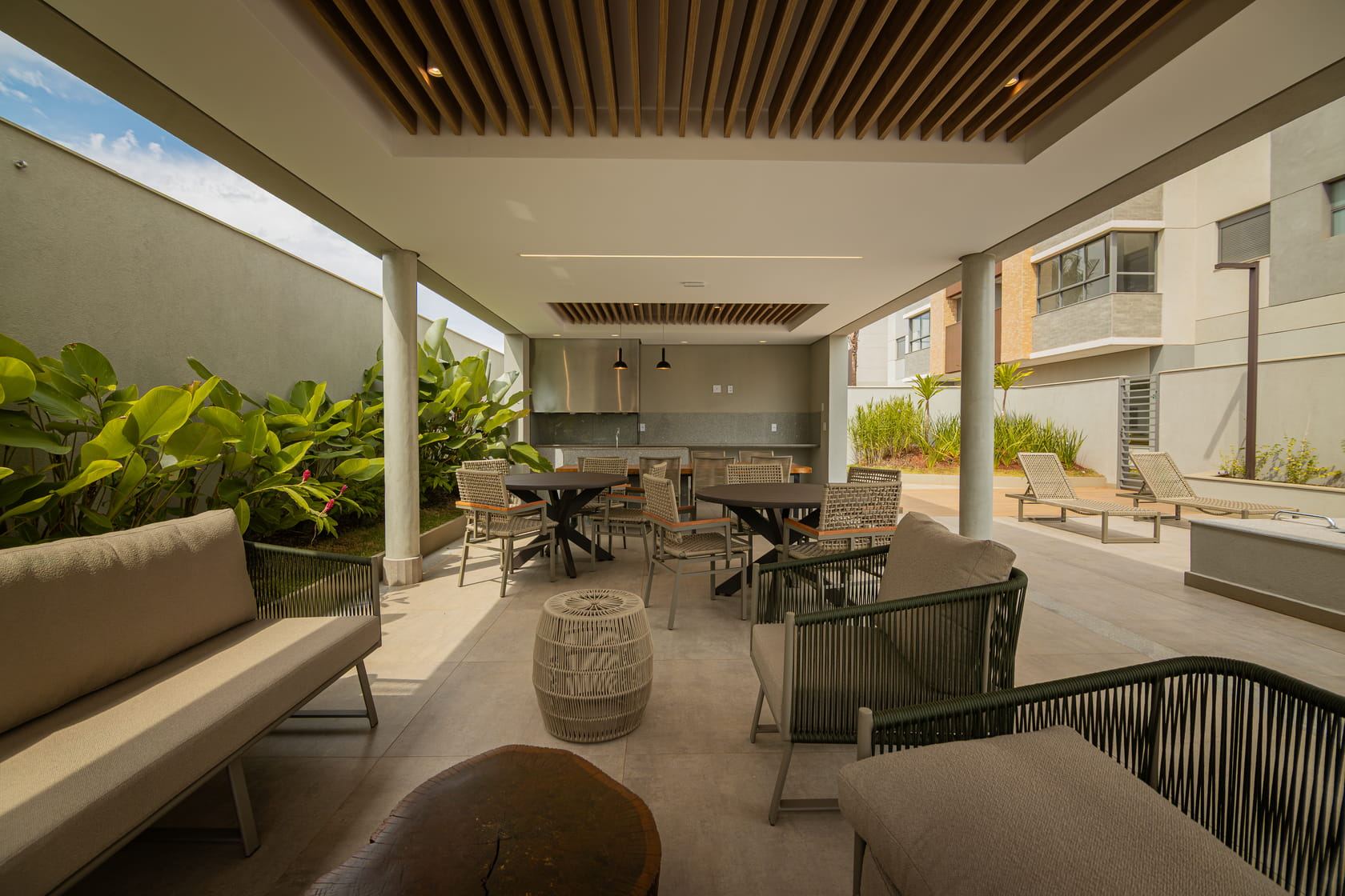 Espaço gourmet coberto com lounge, mesas e churrasqueira
