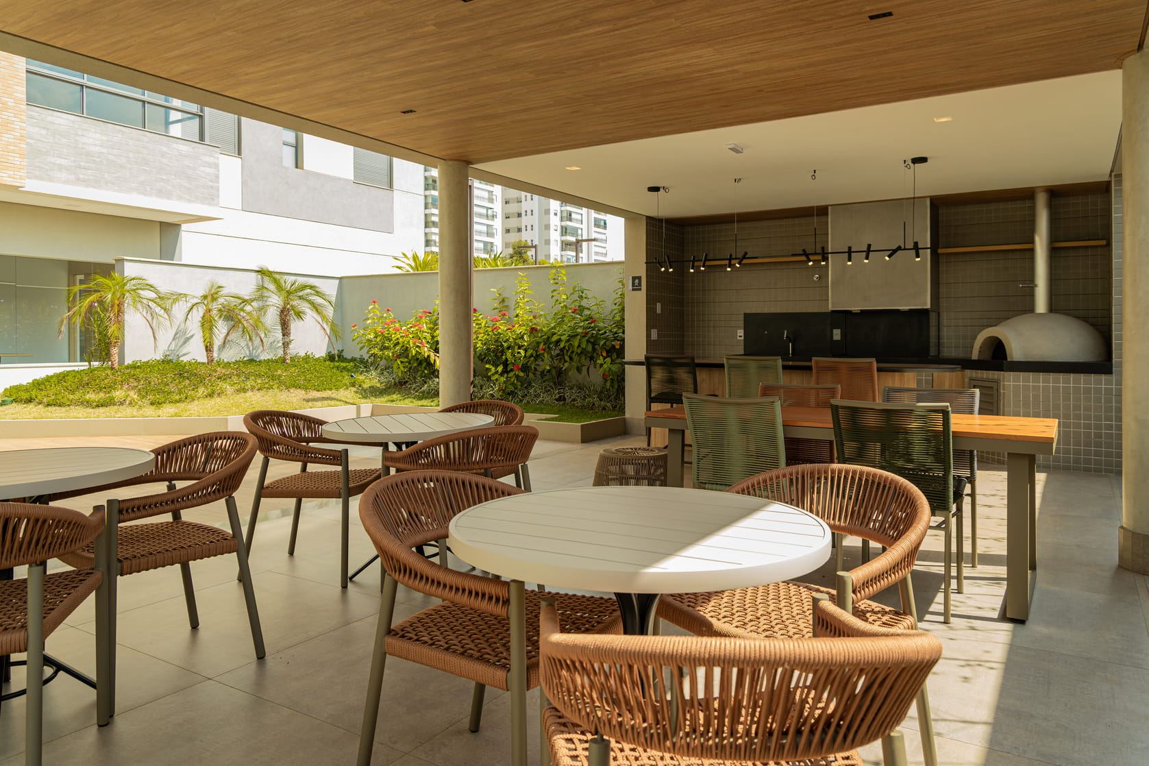 Espaço gourmet com mesas, bancada e forno de pizza